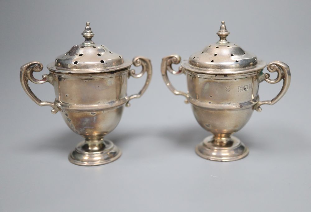 A cased pair of late Victorian small silver trophy shaped pepper pots, Horace Woodward & Co, London, 1899, 67mm,